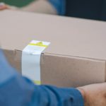 up close image of mailman handing box to customer to return