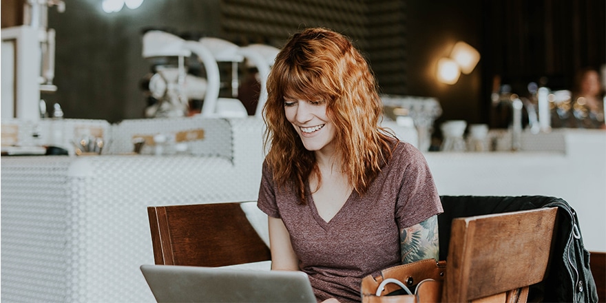 woman looking at computer and smiling possibly committing friendly fraud 